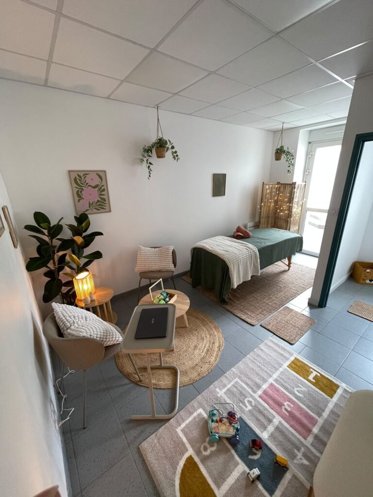 bureau lumineux avec un tapis au sol, deux sièges, des plantes et une table de massage